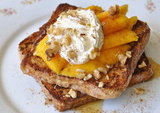 Wheat bread French toast topped with sliced fresh mangoes, honey, whipped cream and chopped walnuts