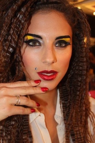 For the lips, artists applied red glitter on top of lipstick. Then, gloss was added on top of that. For the final touch came a dramatic blue diamond mole.
For the lips, artists applied red glitter on top of lipstick. Then, gloss was added on top of that. For the final touch came a dramatic blue diamond mole.