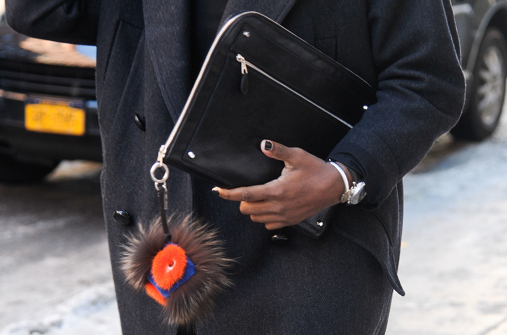 Perfect Fashion Week accessories include a Fendi charm and sleek clutch. 
