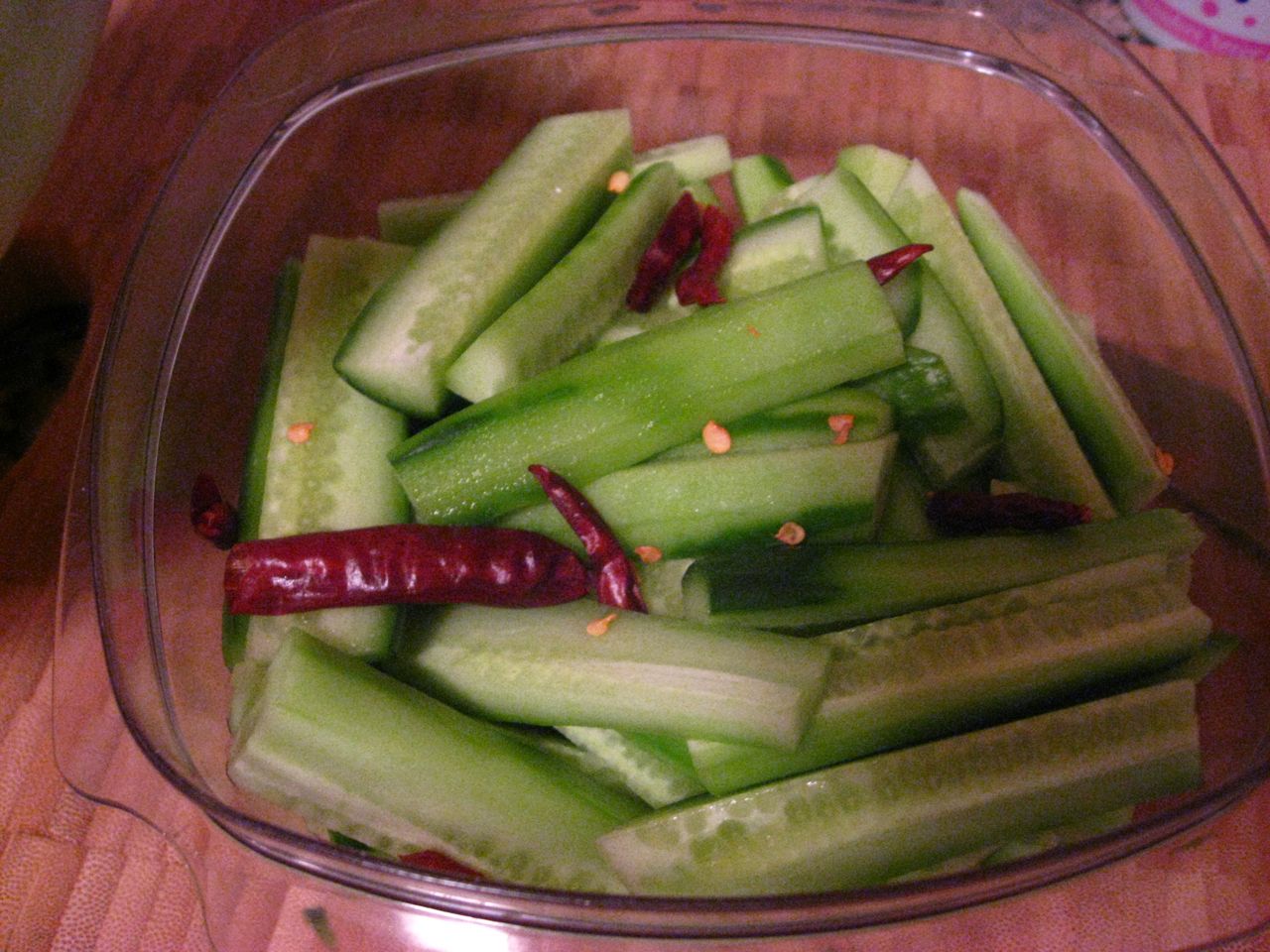 Put the cucumbers and hot peppers into a jar or large sealable vessel. Put the cucumbers and hot peppers into a jar or large sealable vessel.
