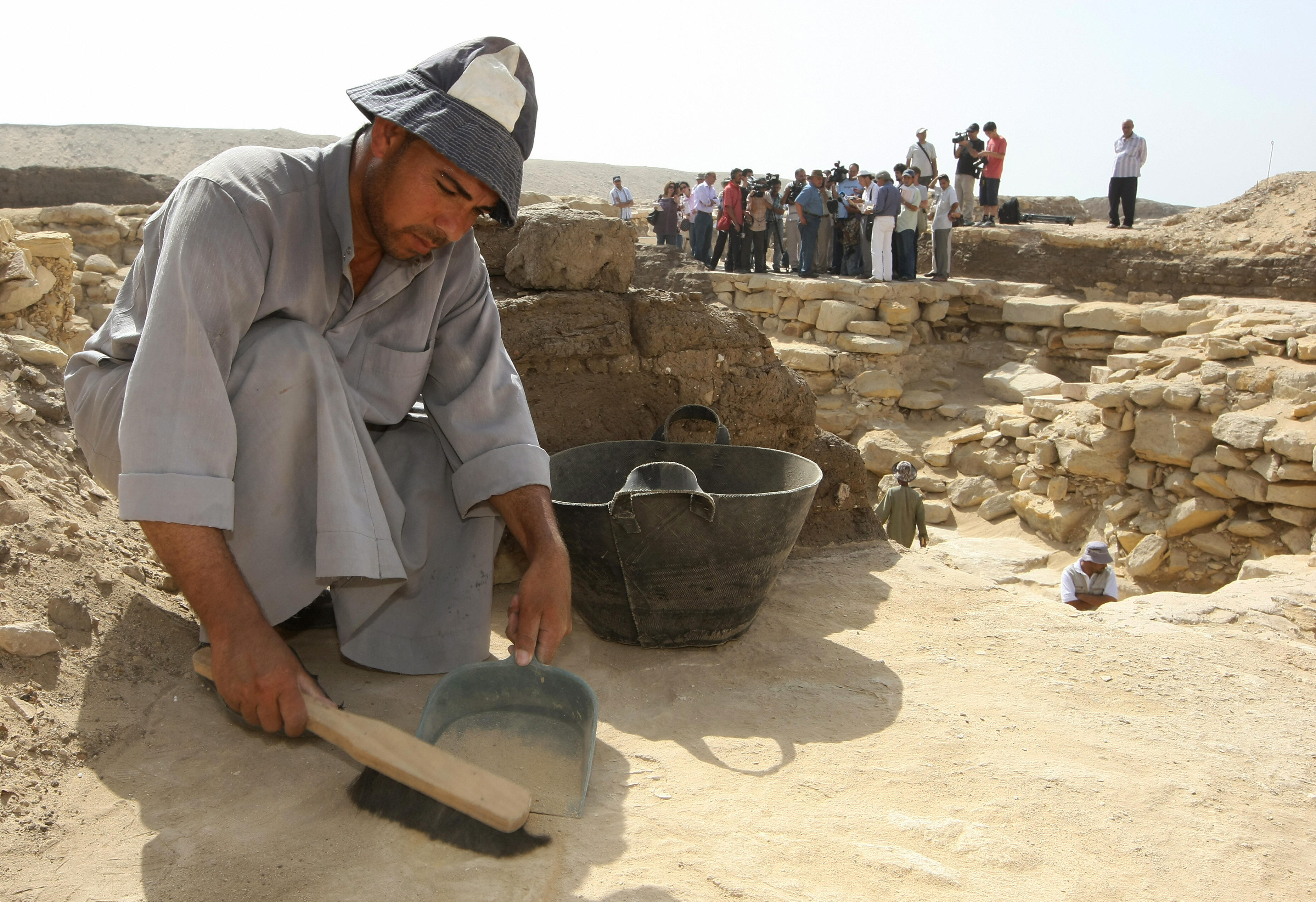 An excavation worker collects sand from the site of an ancient pyramid in Saqqara. An excavation worker collects sand from the site of an ancient pyramid in Saqqara.