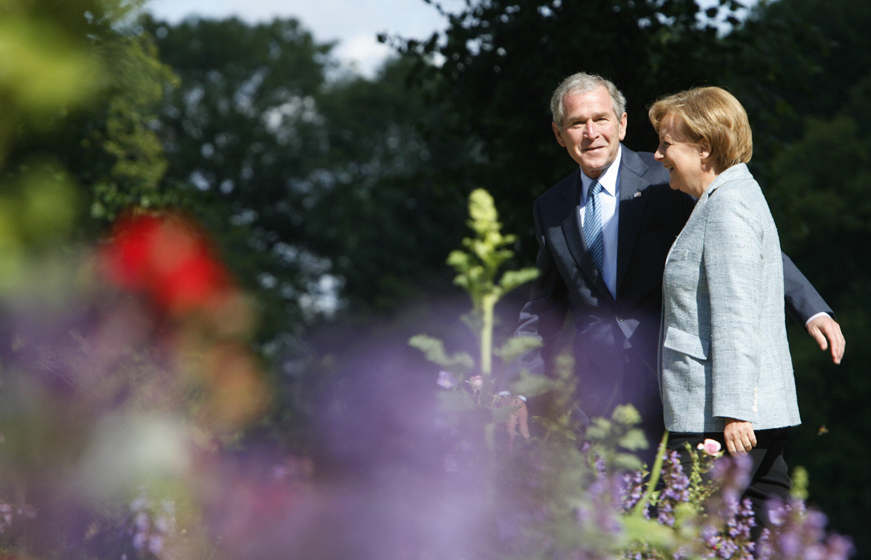 Bush and German Chancellor Angela Merkel walk around the gardens at the guest house of the Federal Republic. Bush and German Chancellor Angela Merkel walk around the gardens at the guest house of the Federal Republic.